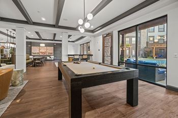 A billiard table is in the middle of a room with wood flooring.